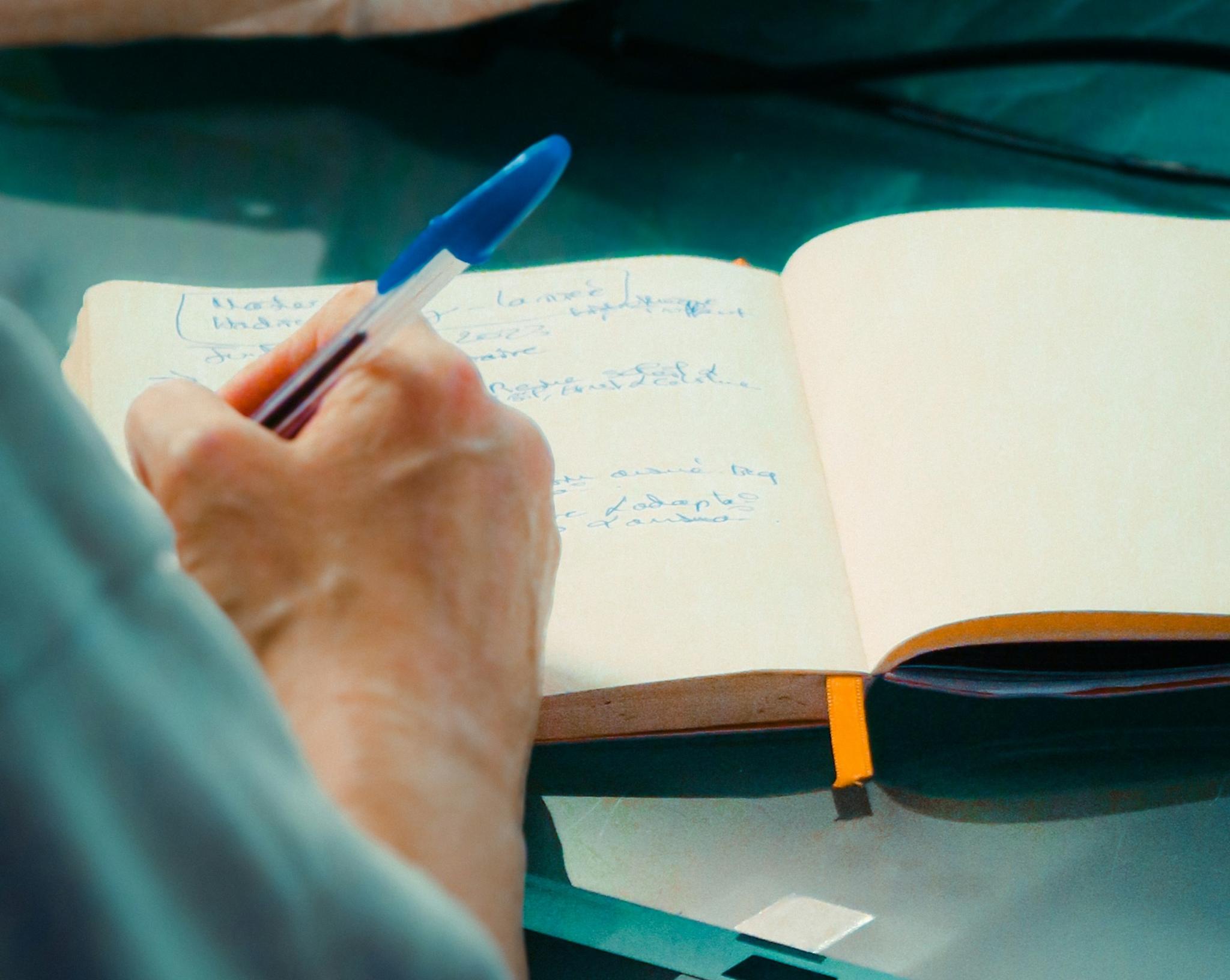 Persona escribiendo con bolígrafo sobre una libreta