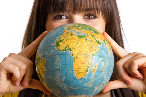 Aparece la cara de una mujer detrás de una bola del mundo que sostiene con sus manos