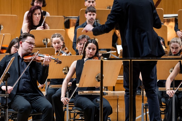 Varias personas de una orquesta de música tocando el violín