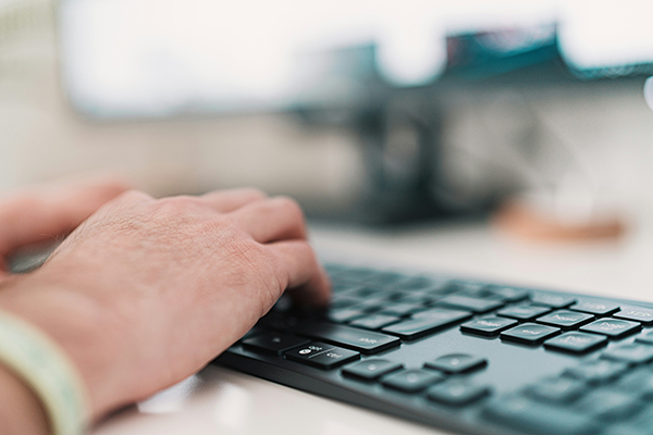 Se muestra una mano escribiendo en un teclado simulando que puede estar teletrabajando